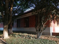 斜阳照在校园里的老建筑和植物上，有个学生在背英语，画面很美