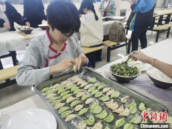 图为一名学生和同学一起动手包饺子。　刘鹏 摄
