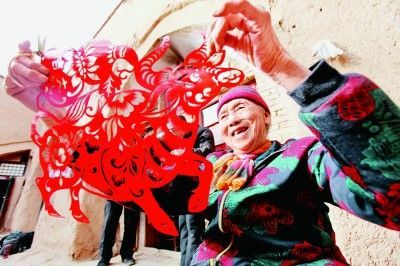     河南三门峡陕州区西张村镇南沟村，83岁的民间艺人员月英展示牛年剪纸作品。孙猛摄/光明图片