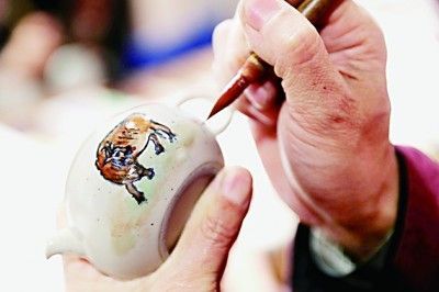     山东青岛的一位市民在瓷器上描绘五牛图。张进刚摄/光明图片