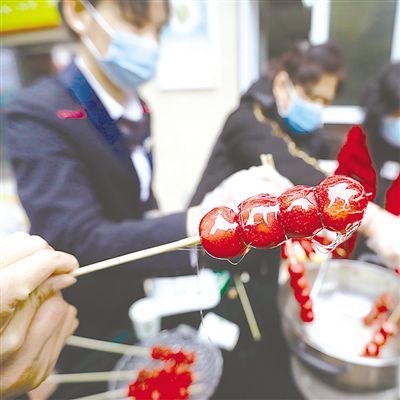 陕西西安市曲江金地湖城大境天字一号小区的物业办公室内,物业工作人员和居民一起制作糖葫芦。 资料图片
