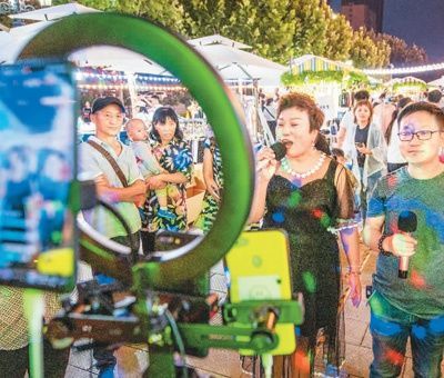　　在山西省运城市华曦广场夜市，有美食、星光音乐、全民K歌等八大主题近百个摊位供市民消费，丰富了市民的夜生活。图为市民正在夜市上用在线K歌平台直播唱歌。　　薛 俊摄（人民图片）