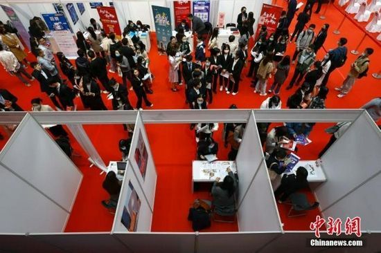 资料图:求职者在招聘会场递交简历。中新社记者 富田 摄