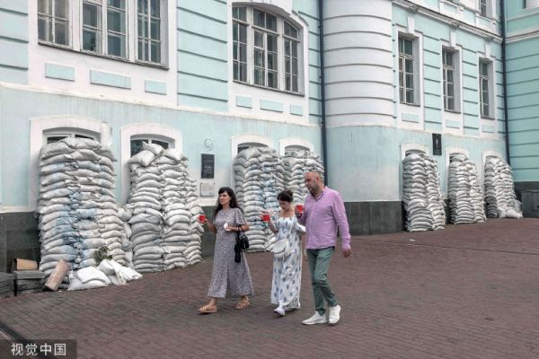 当地时间2023年7月30日，乌克兰基辅，俄乌冲突之际，民众走过保护着Podil社区一栋建筑窗户的沙袋。（视觉中国）