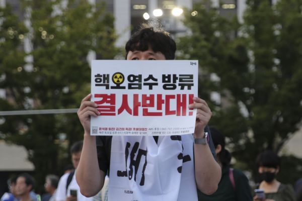 8月26日,市民手举标语在韩国釜山火车站广场前参加集会。图片来源:新华社