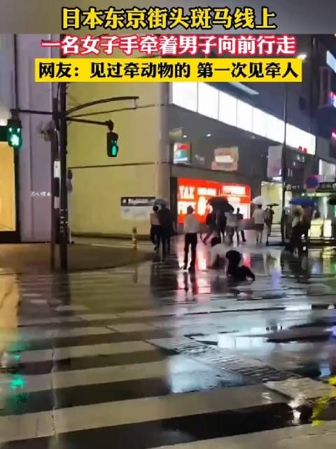 日本东京街头斑马线上,一名女子手牵着男子向前行走!