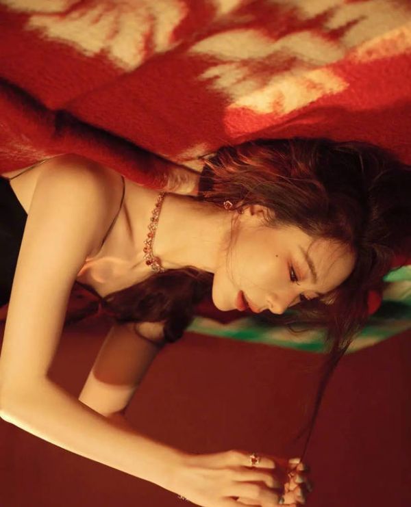 戚薇俯身垂眸，暖光勾勒冷艳侧颜。