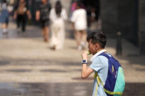 6月23日，在北京前门大街，一位小朋友在吃冷饮消暑。 新华社记者鞠焕宗摄